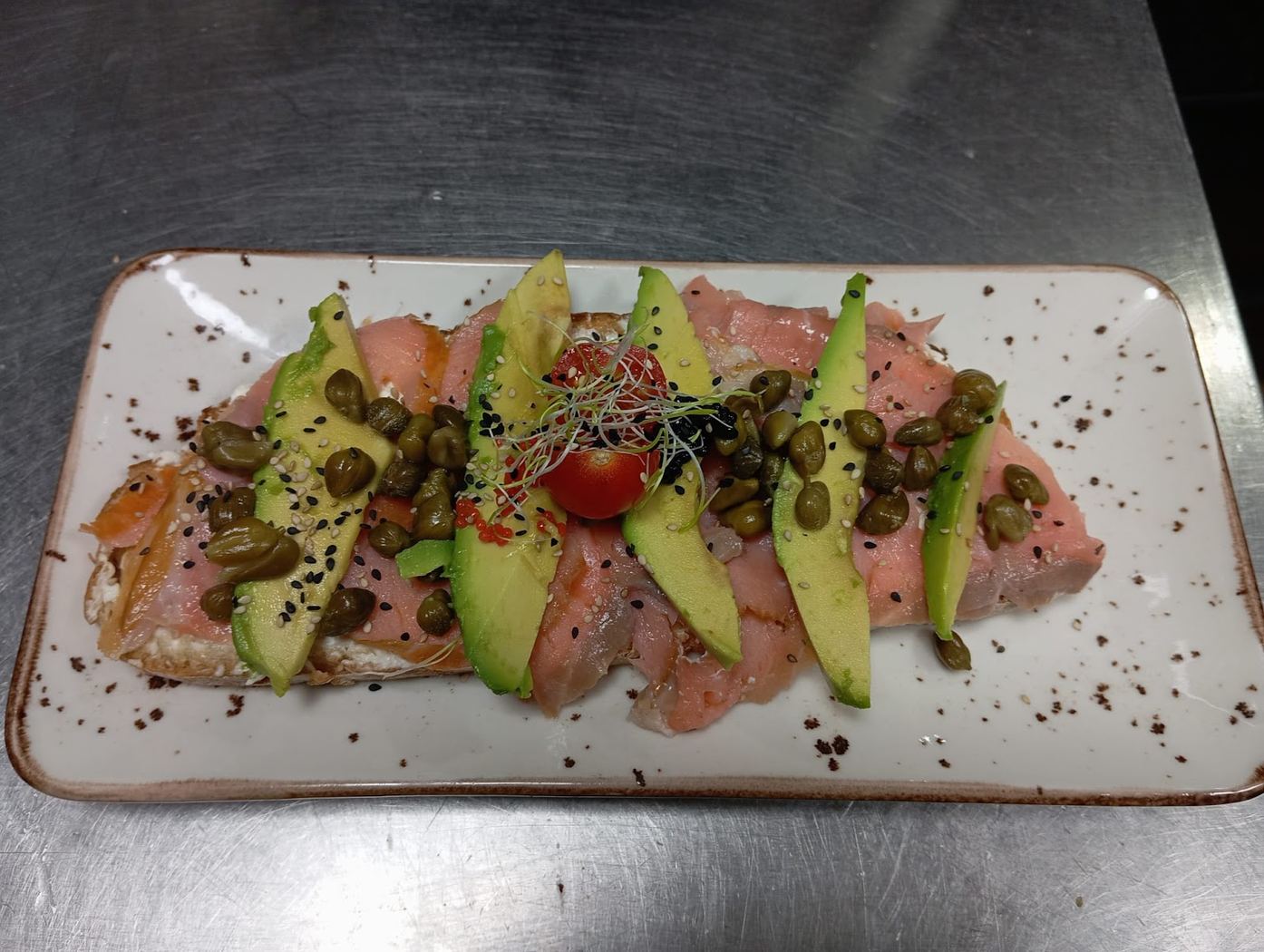 Tostada de salmón ahumado con aguacate fresco, alcaparras y semillas de sésamo